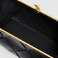 Close-up view of an open Anine Bing Anine Braided Leather Clutch, featuring a black braided leather exterior with a gold metal frame and clasp, showcasing its empty black fabric interior.