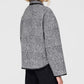 A person with blonde hair is seen from the back wearing the Anine Bing Camden Jacket in gray and black plaid wool blend, paired with black pants, against a plain light background.