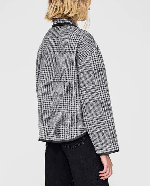 A person with blonde hair is seen from the back wearing the Anine Bing Camden Jacket in gray and black plaid wool blend, paired with black pants, against a plain light background.