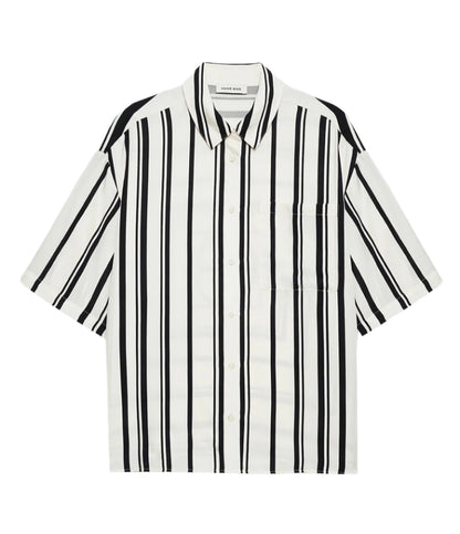 The Anine Bing Coco Shirt Monogram Stripe is a boxy collared shirt in a lightweight cupro blend with ivory and black vertical stripes, short sleeves, and a chest pocket, shown laid flat on a white background.