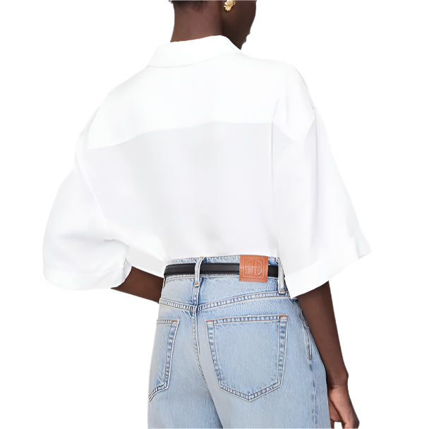 A person is seen from the back wearing the Anine Bing Coco Shirt in ivory, loosely tucked into light blue high-waisted jeans.