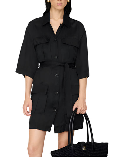 A woman wearing the Anine Bing Geri Dress—a washed black cupro dress with a waist tie and large front pockets—holds a black woven tote bag.