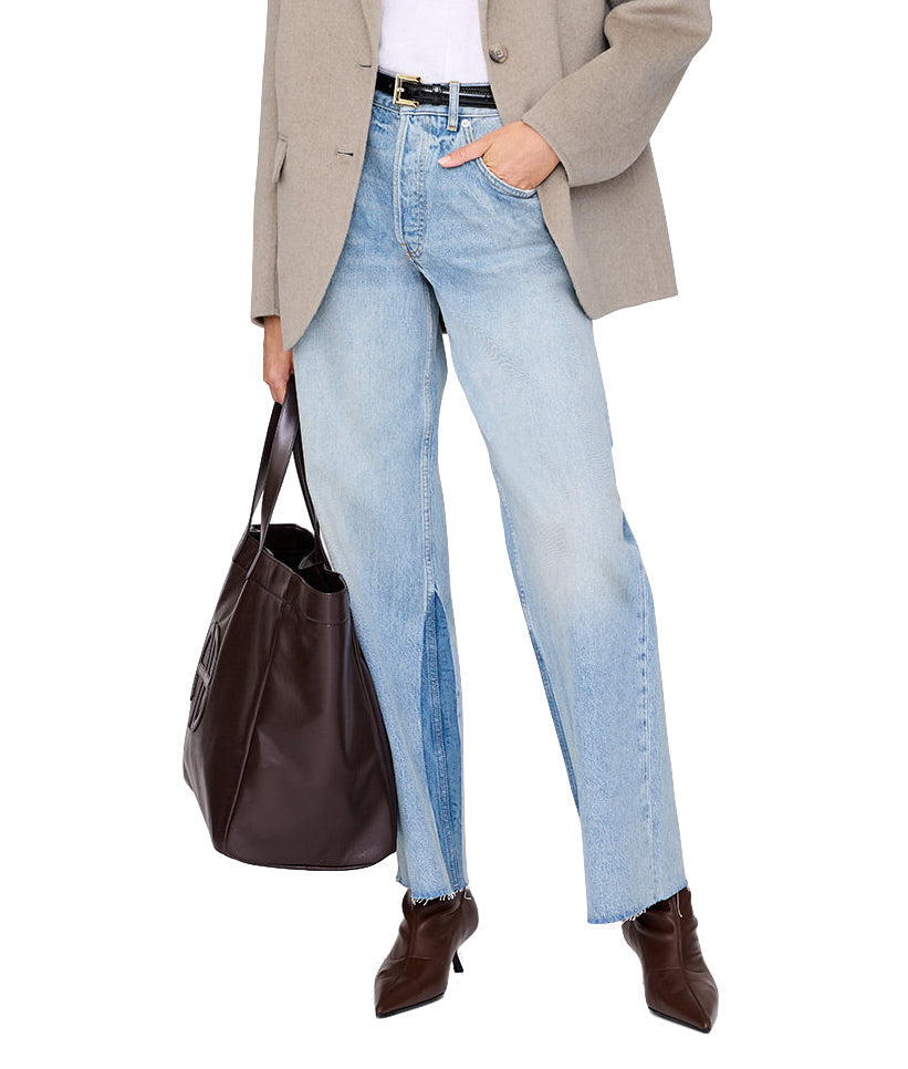 Person styles light-wash jeans with a front slit, a beige blazer, and brown pointed boots, carrying the Anine Bing Large Rio Tote—an essential accessory that adds chic style to any outfit.