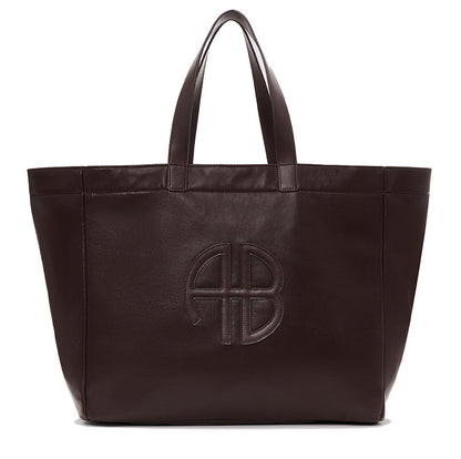 The Large Rio Tote by Anine Bing is a spacious dark brown leather bag with two handles and an embossed circular AB logo on the front—an essential for everyday use.