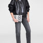 A woman wearing a black leather jacket, gray shirt, gray jeans, and snakeskin-patterned flats holds the Anine Bing Elly Large Pouch with a chic python print against a plain background.