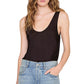 A person wearing the Anine Bing Lea Top in black silk charmeuse and light blue jeans, with one hand in their pocket, shown from shoulders to hips.