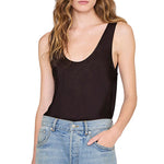 A person wearing the Anine Bing Lea Top in black silk charmeuse and light blue jeans, with one hand in their pocket, shown from shoulders to hips.