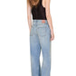 A person with long wavy hair, seen from behind, wears the Anine Bing Lea Top in black silk charmeuse paired with light blue high-waisted wide-leg jeans for a relaxed silhouette.