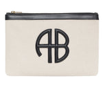 The Lili Canvas Pouch from Anine Bing is a beige cotton clutch with a black zipper and a black leather "AB" monogram on the front, inspired by the brand’s iconic Lili Bag.