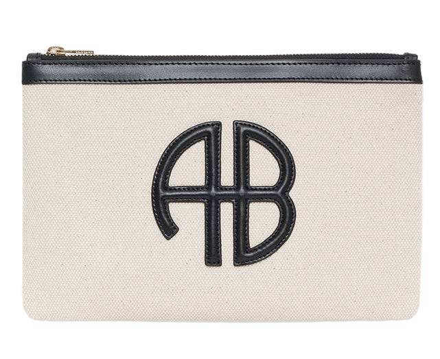 The Lili Canvas Pouch from Anine Bing is a beige cotton clutch with a black zipper and a black leather "AB" monogram on the front, inspired by the brand’s iconic Lili Bag.