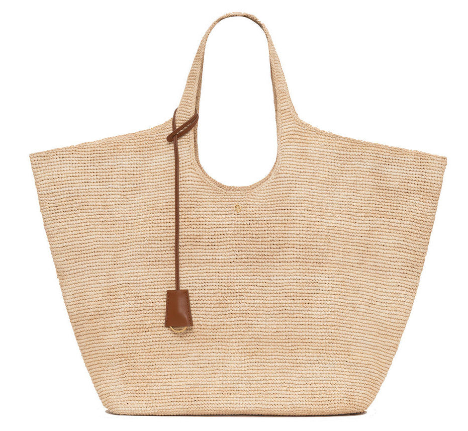 The Lili Raffia Tote by Anine Bing is a spacious handwoven bag featuring two handles and a brown leather strap detail, shown here on a white background—an everyday carryall ideal for any outing.