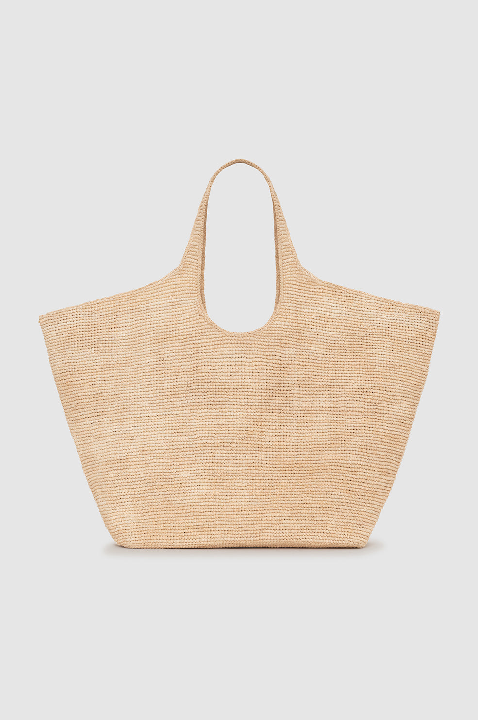 The Lili Raffia Tote by Anine Bing is a beige handwoven raffia bag featuring two handles, shown against a plain light background—an oversized tote that’s ideal for use as your everyday carryall.