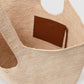 The Lili Raffia Tote by Anine Bing, handwoven in beige raffia and finished with an interior brown leather pocket, is photographed from above to showcase its roomy interior—making it the ideal everyday carryall.
