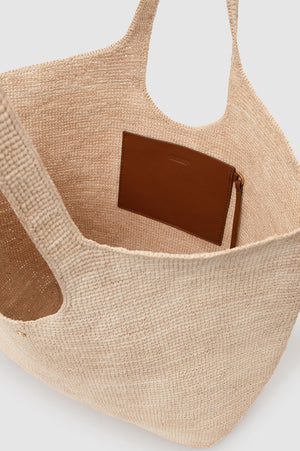 The Lili Raffia Tote by Anine Bing, handwoven in beige raffia and finished with an interior brown leather pocket, is photographed from above to showcase its roomy interior—making it the ideal everyday carryall.