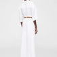 A person stands facing away, wearing the Anine Bing Lou Trouser Linen—breathable wide-leg trousers with a brown belt—and a white short-sleeve top, set against a plain white background.