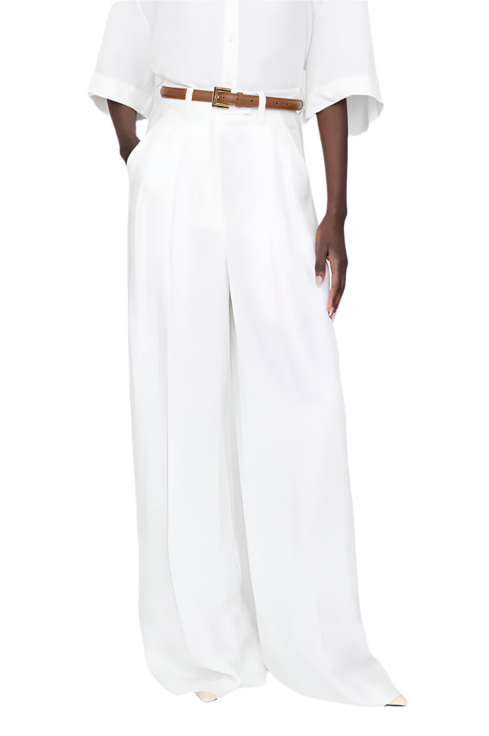 A person wears the Anine Bing Lou Trouser Linen—high-waisted, wide-leg, breathable linen-blend pants—paired with a white button-up shirt and brown belt, standing against a plain background.