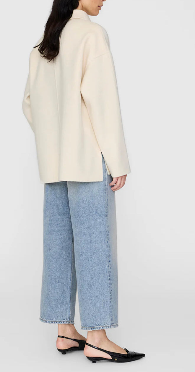 A person wearing the Anine Bing Luca Cashmere Blend Jacket, light blue wide-leg jeans, and black slingback flats stands against a plain background.