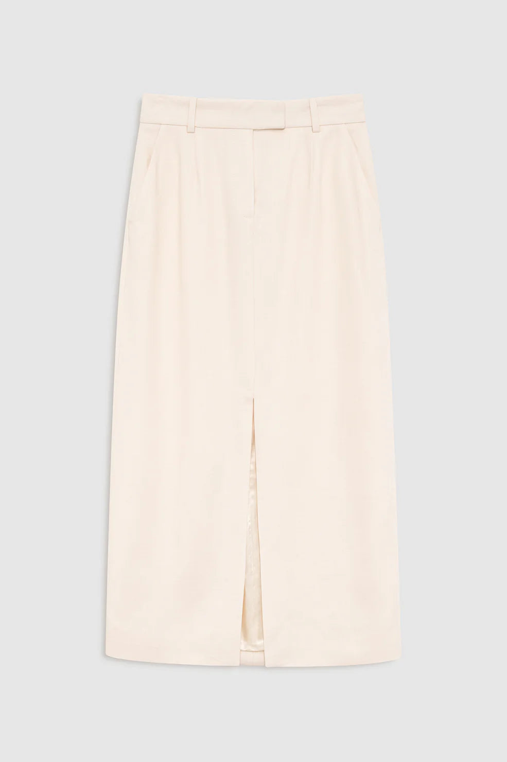 The Meredith Skirt by Anine Bing, a beige knee-length tailored piece featuring a front slit, belt loops, and side pockets, is displayed flat against a plain grey background.