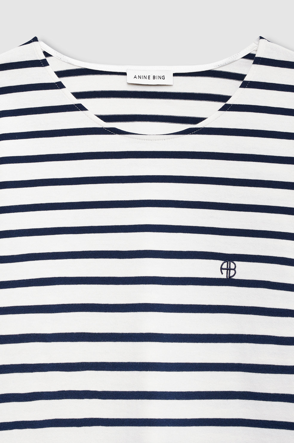 The Newton Tee by Anine Bing is a navy striped long sleeve shirt with a relaxed fit, featuring an "AB" embroidered logo on the chest and an "ANINE BING" label at the boat neckline.