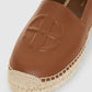Close-up of the Paloma Espadrilles by Anine Bing, featuring a brown leather upper embossed with "AB" initials and a woven jute sole.