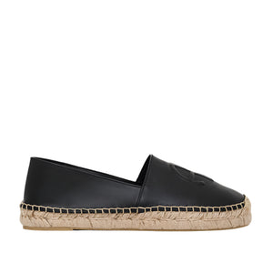 The Paloma Espadrilles from Anine Bing feature a sleek black leather finish with a woven jute sole and an embossed front monogram, combining elegance with comfort in a classic slip-on design.