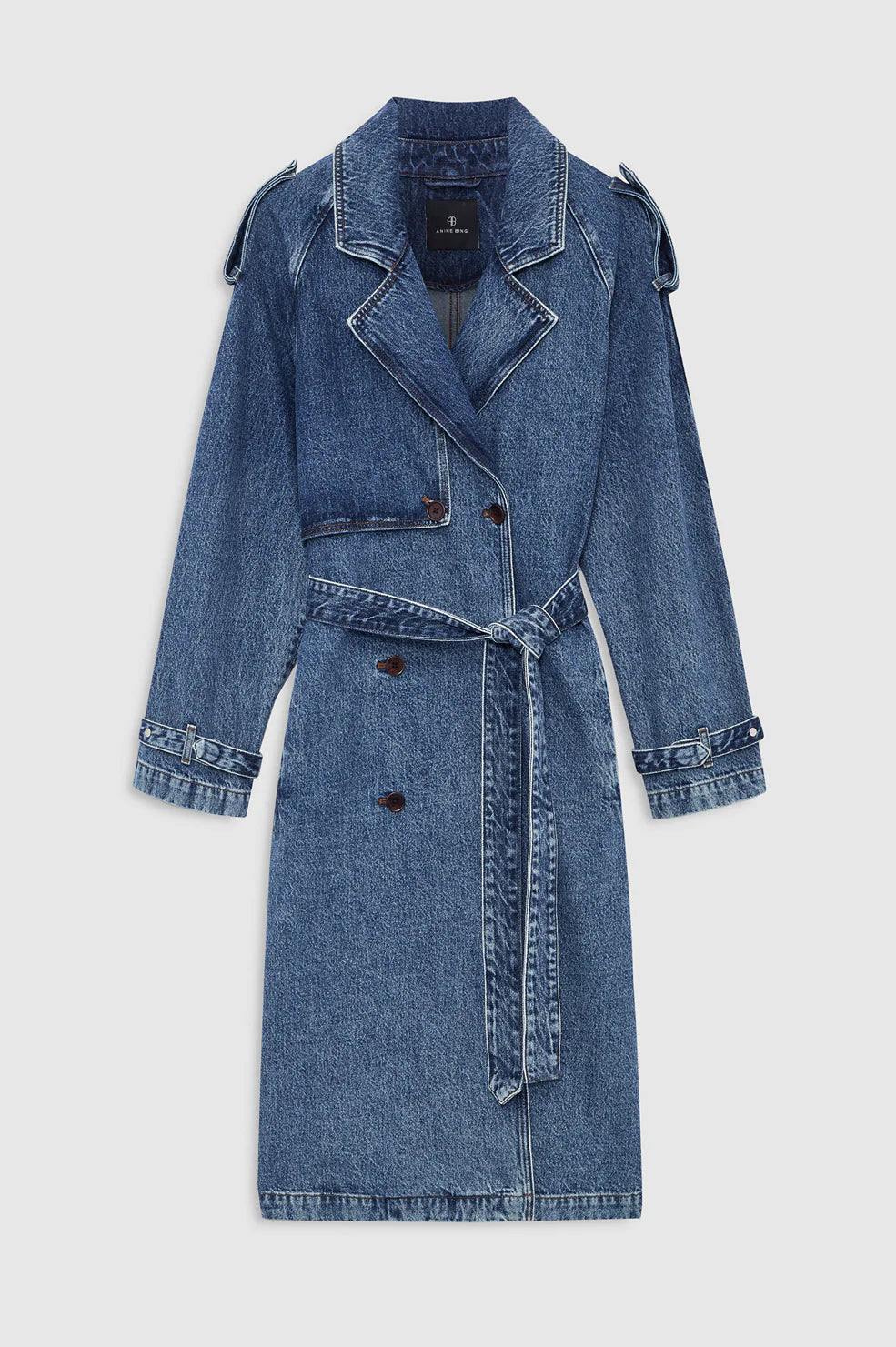 The Rickie Maxi Denim Trench by Anine Bing is a long-sleeved blue cotton denim coat featuring a notched collar, button front, waist belt, and adjustable cuffs, designed in a classic menswear-inspired silhouette and shown against a plain background.