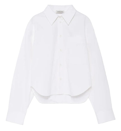 The Scott Cropped Shirt by Anine Bing is a white long-sleeve button-up featuring a collar, chest pocket, and subtly curved hem. Made from crisp cotton poplin for comfortable wear, it boasts a relaxed silhouette and is showcased against a plain white background.
