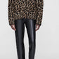 Model wears the Anine Bing Sydney Crew Sweater in leopard print with chunky open-weave moss stitch, black leather pants, and black pointed-toe ankle boots against a plain light background.