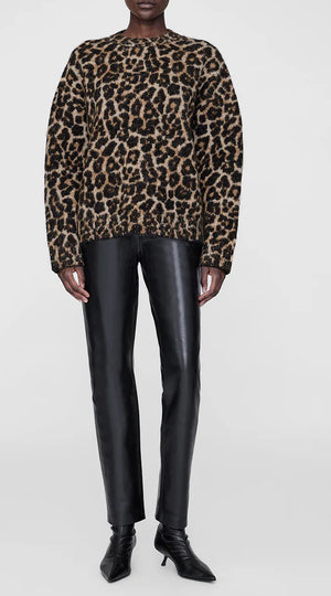 Model wears the Anine Bing Sydney Crew Sweater in leopard print with chunky open-weave moss stitch, black leather pants, and black pointed-toe ankle boots against a plain light background.