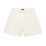 The Trent Short by Anine Bing is a high-waisted, cream-colored suiting short with belt loops and front pleats, shown on a white background.