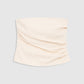 The Tyla Top by Anine Bing is a beige, strapless bandeau featuring subtle ruched detailing on one side and displayed against a plain gray background. With its sculpted shape that flatters the silhouette, this versatile top is a chic addition to any wardrobe.