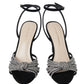 A pair of Loeffler Randall Ada Black Knot Heeled Sandals, featuring black suede straps embellished with rhinestones and the brand name "Loeffler Randall" printed on the insoles.