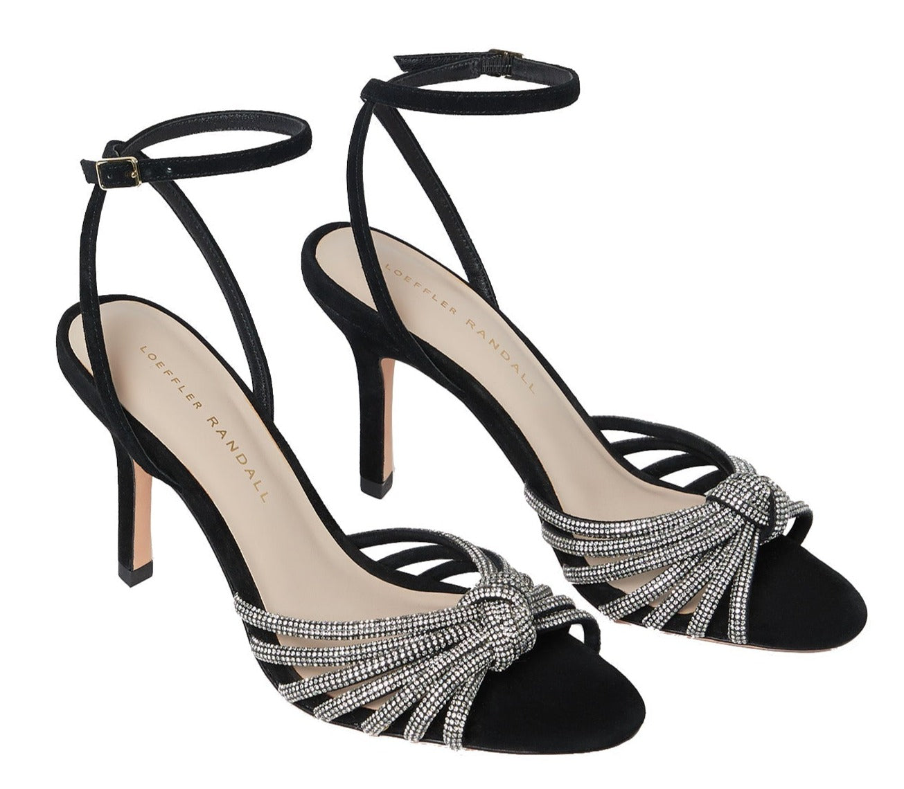 A pair of black suede high-heeled sandals with ankle straps and rhinestone detailing on the front, named "Loeffler Randall Ada Black Knot Heeled Sandal," featuring the "Loeffler Randall" label on the insole.