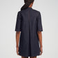 A person with braided hair, seen from behind, is wearing the Adam Lippes Lauder Dress—a dark Japanese indigo denim short-sleeve dress featuring a center back pleat and subtle topstitching.