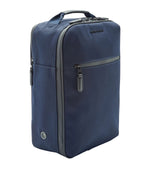 A navy blue rectangular Peter Millar Pursuit Shoe Bag with a top handle, genuine leather trim, front zipper pocket, side vent, and two side zippers is shown standing upright on a white background.