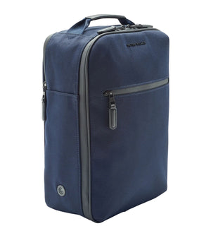 A navy blue rectangular Peter Millar Pursuit Shoe Bag with a top handle, genuine leather trim, front zipper pocket, side vent, and two side zippers is shown standing upright on a white background.
