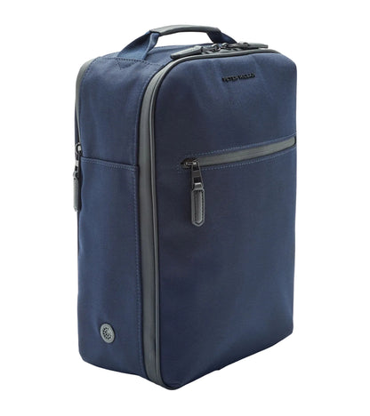 A navy blue rectangular Peter Millar Pursuit Shoe Bag with a top handle, genuine leather trim, front zipper pocket, side vent, and two side zippers is shown standing upright on a white background.