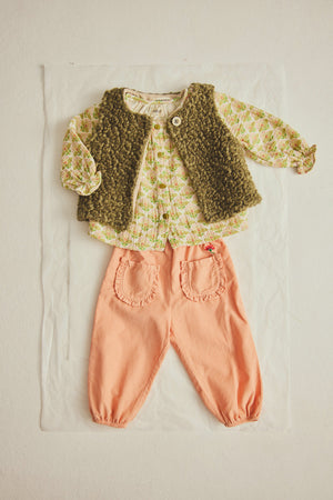 A baby outfit featuring a patterned long-sleeve top, a textured green vest, and Cozmo Baby Girls’ Agen Corduroy Pants in peach with ruffled pockets, laid flat on a white background.