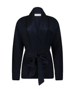 The Alba Blouse by Victoria Beckham is a black long-sleeve top with a shawl collar and matching fabric belt tied at the waist, featuring an elegant drape, displayed on a plain white background.