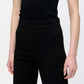 A person wears the Callas Milano Anouk Pant, a high-waisted travel pant, paired with a sleeveless black top. They are shown from shoulders to mid-thigh against a plain background.