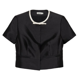 Simkhai Naelle Top in structured black satin, featuring a cropped short-sleeve silhouette, white crew neckline, and a small decorative bow at the center.