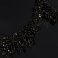 Close-up of the Simkhai Zoriel Gown, featuring a black crepe neckline embellished with dark beads and hanging crystal fringe.