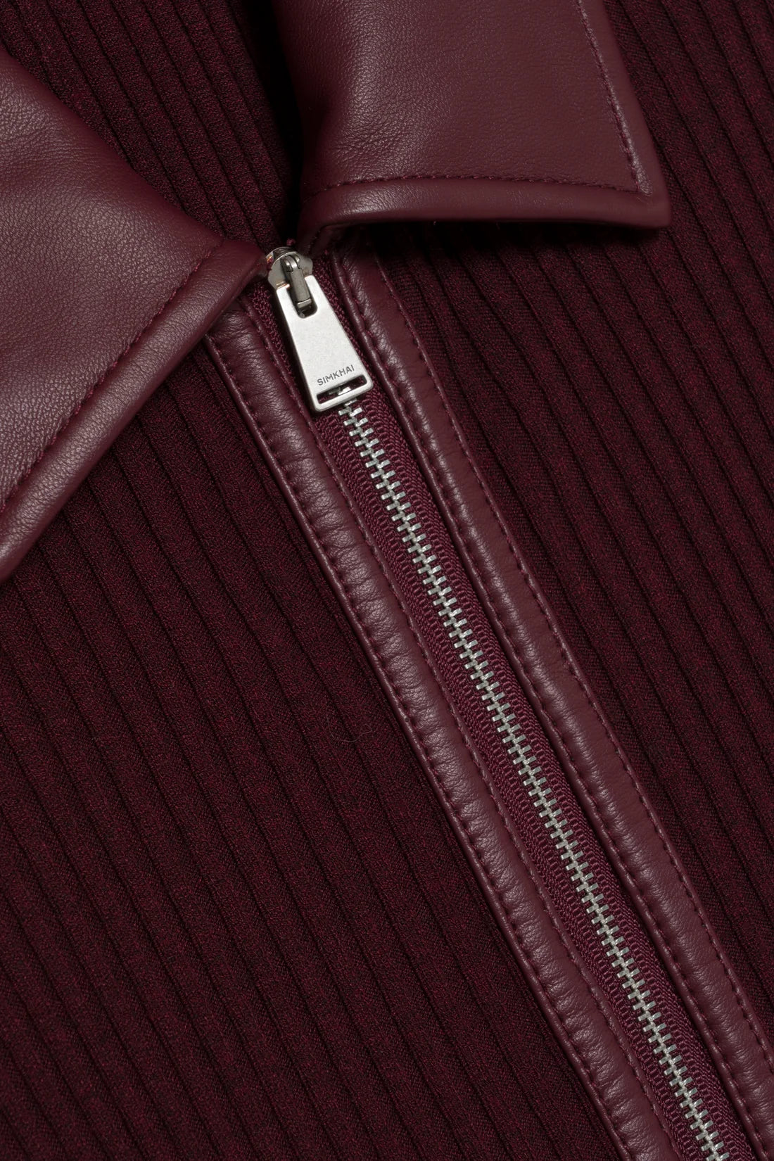Close-up of the Simkhai Ismelle Midi Dress in burgundy, showcasing its ribbed knit fabric, silver partially unzipped zipper, and distinctive leather collar.