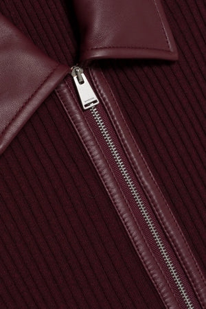 Close-up of the Simkhai Ismelle Midi Dress in burgundy, showcasing its ribbed knit fabric, silver partially unzipped zipper, and distinctive leather collar.