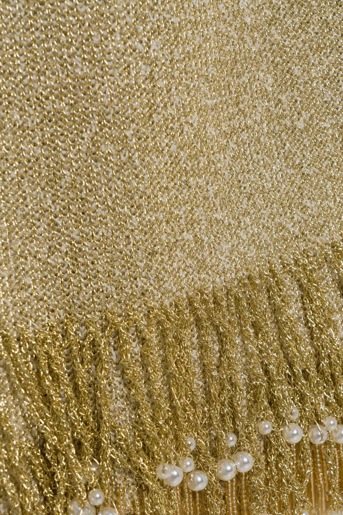 Close-up of the metallic gold bouclé Zeni Midi Skirt with a fringed hem accented by small white pearls.