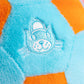 Close-up of soft blue and orange plush fabric with an embroidered cartoon cat in a cap, inspired by the playful Jellycat Football from Jellycat.