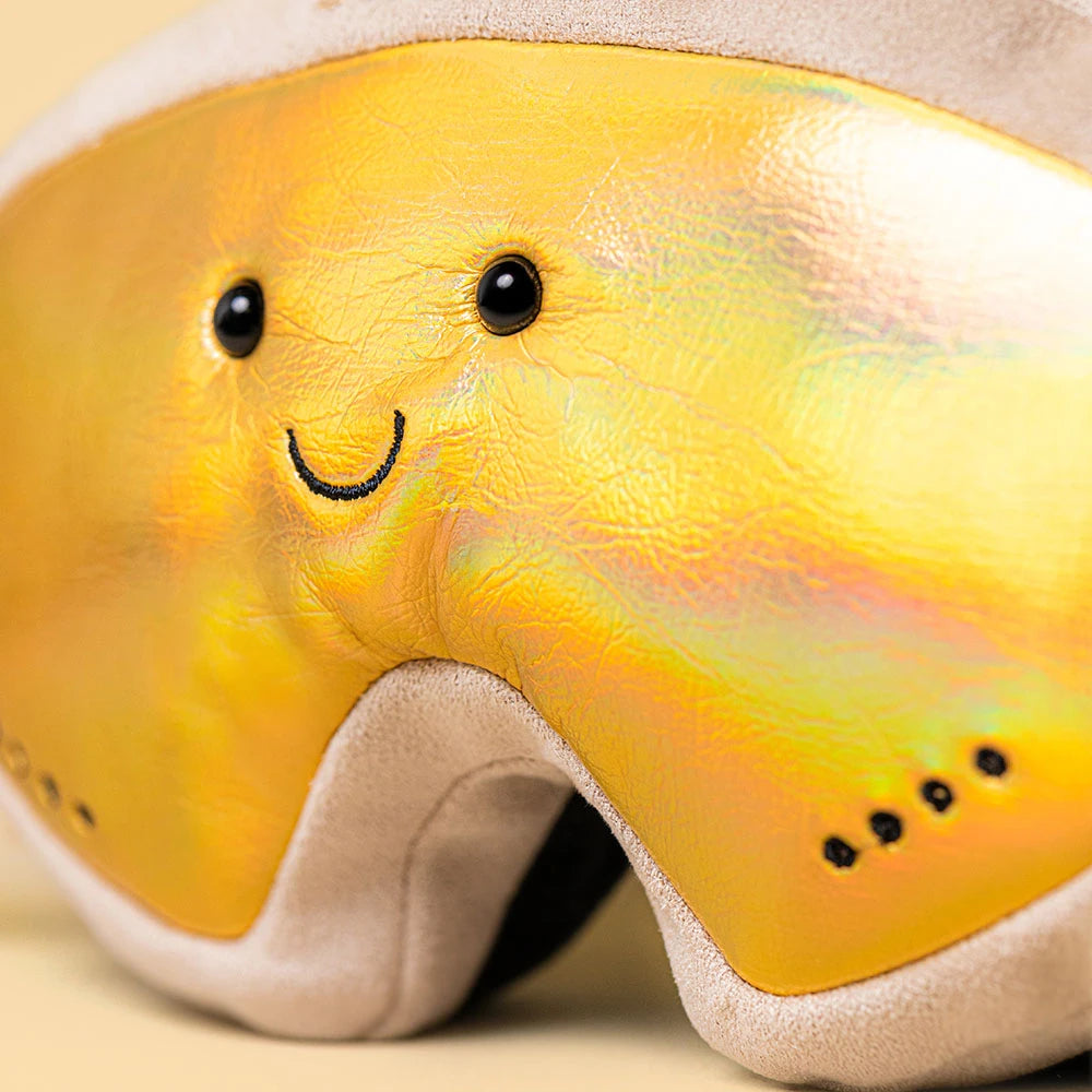 Jellycat Amuseables Sports Ski Club Goggles in iridescent yellow with a smiling face, black eyes, and a stitched mouth.
