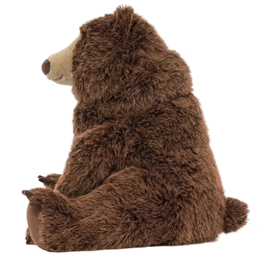Bizzlestomp Bear by Jellycat—a plush brown stuffed animal sits upright, showing its soft fur and a gentle smile in profile.