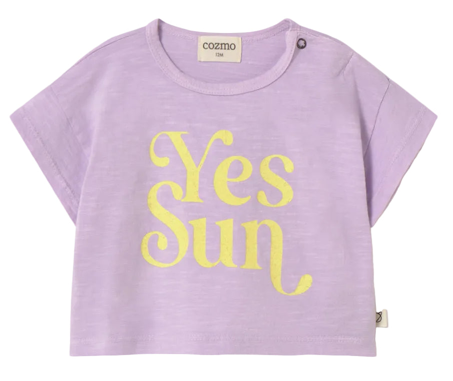 The Cozmo Baby Girls' Aura T-Shirt is a lightweight cotton top in light purple, featuring a bold yellow "Yes Sun" print on the front and a button detail on the left shoulder.