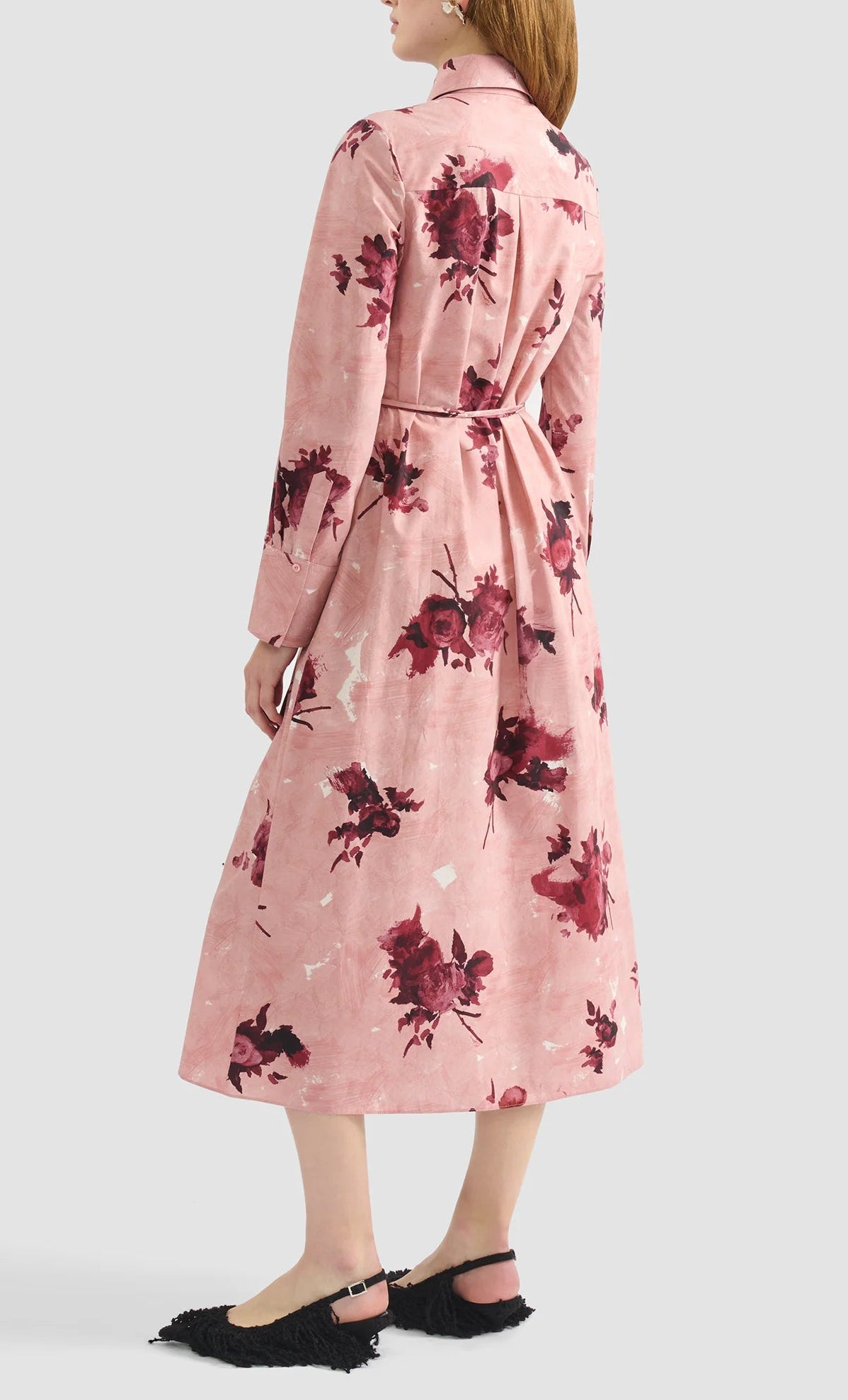 A woman is shown from the back wearing the Erdem Long Sleeve Abstract Rose Shirt Dress with a belted waist, paired with black textured flat shoes.